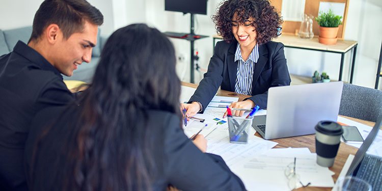 Banker walking entrepreneurs through the business loan documents needed to buy a business.