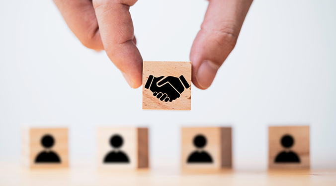 Partnership symbol of handshake on wooden cubes.