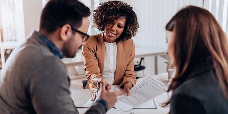 Business sale closing meeting with attendees signing contracts.