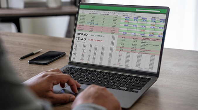 Laptop computer on desk with spreadsheet displayed.