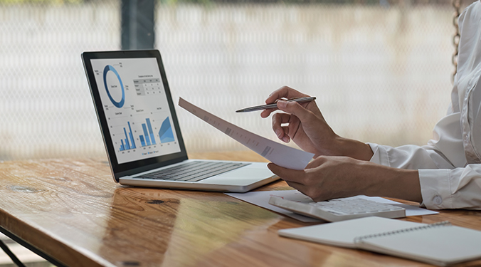 An accountant valuing a business sitting at a desk and reviewing documents and a computer. 