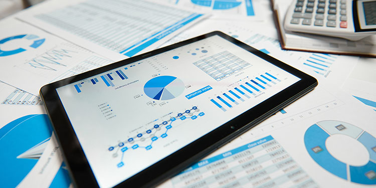 Accounting spreadsheets displayed on tablet, computer, and paper.