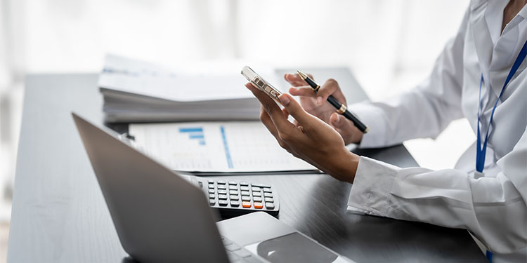 Small business owner at computer working on financial documentation to prepare business for sale.