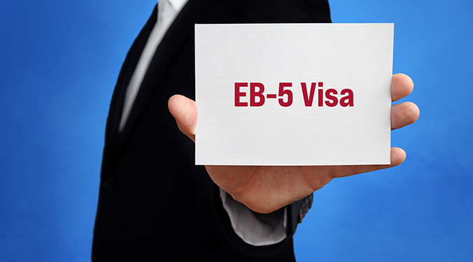 Business person holding a white card that reads, "EB-5".