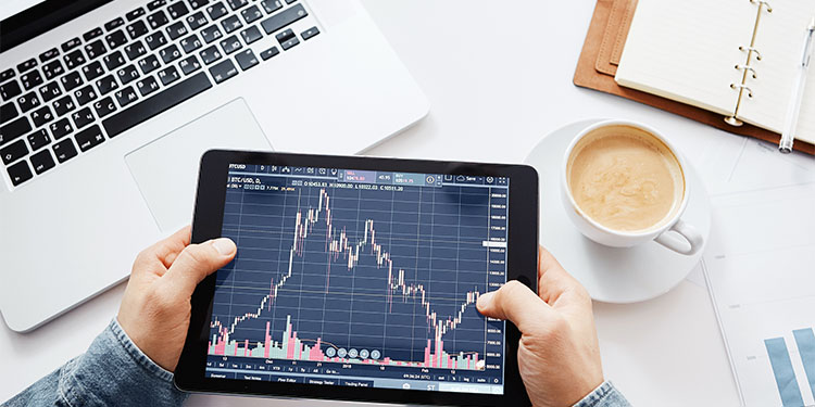 Business owner looking at economic data on a tablet at their workstation. 