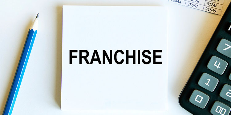 The word 'franchise' written on a notepad, placed on a desk.