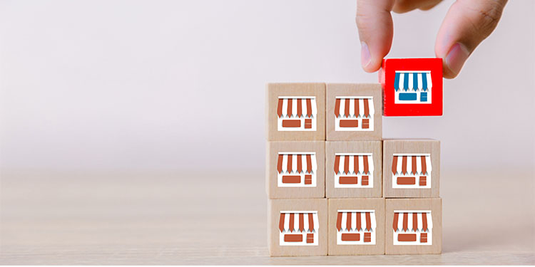 Franchise storefronts depicted on wooden blocks with one red block signifying selling a franchise unit.