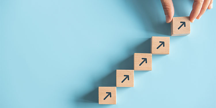 Wooden blocks with arrows pointing up displayed against light blue background.