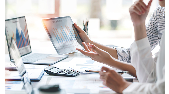 Business operations and financials displayed on computer and tablets with spreadsheets and charts. 