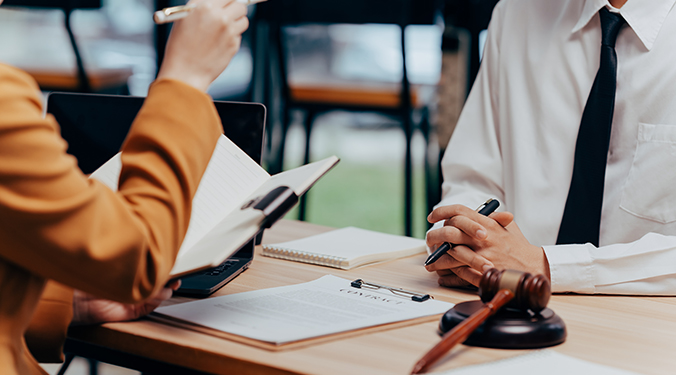 Lawyer counseling small business owner on legal issues at a table with paperwork and gavel. 
