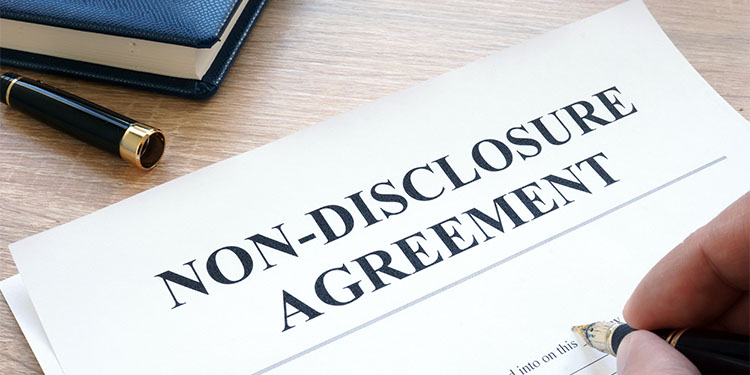 A non-disclosure agreement on a desk being signed with a fountain pen. 