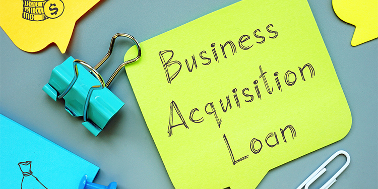 The term 'business acquisition loan' written on green post it note.