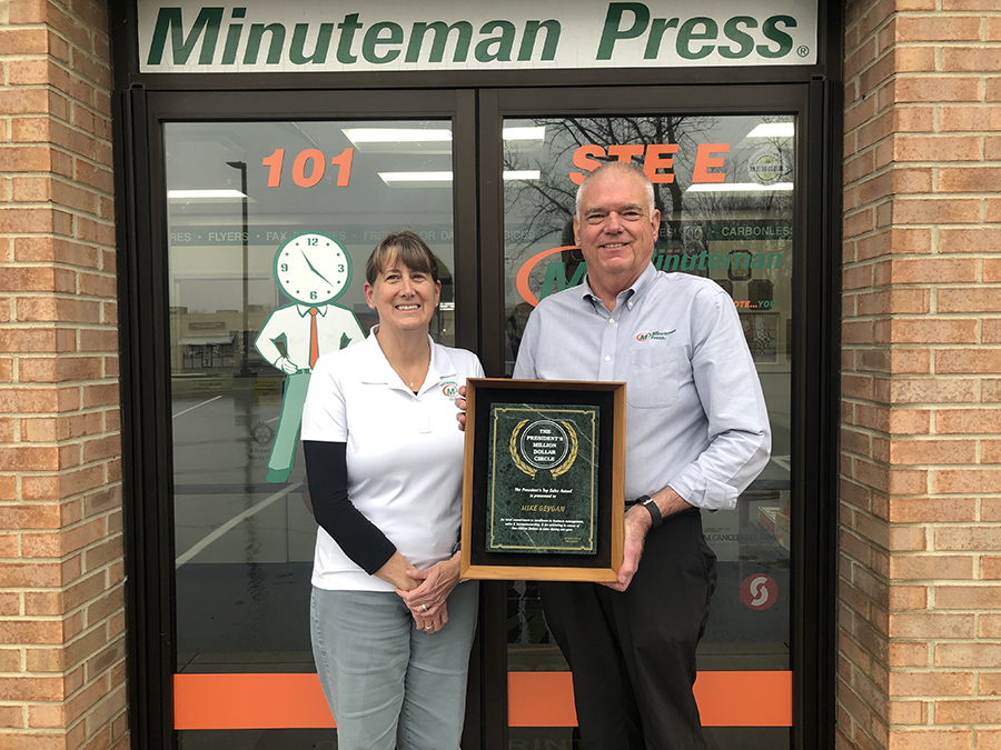 Minuteman Press, Lebanon, Ohio: Retiring owners Karen and Mike Geygan with their President’s Million-Dollar Circle Award in 2022. They have sold the business to new owners Frank and Melissa Hiti. Husband and wife small business owners holding an award in front of their print shop.