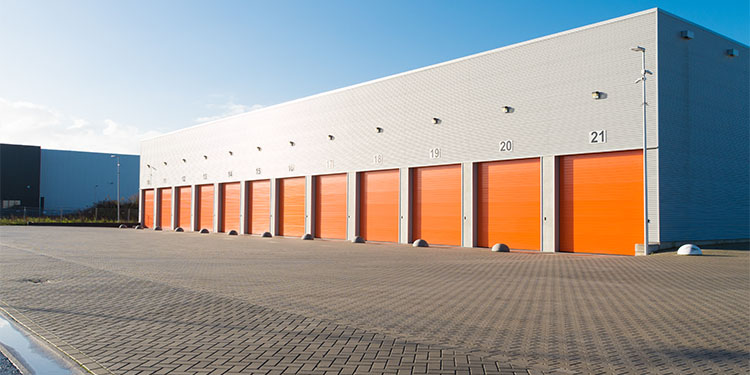 Commercial real estate showing warehouse with 12 orange garage doors for logistics. 