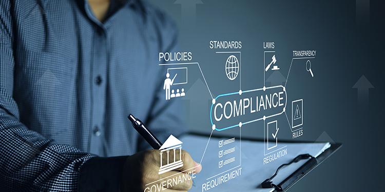 The words 'regulatory compliance' overlayed on image of business owner at computer. 