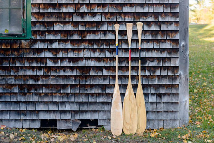 Wooden oars leaning up against wooden shingle barn in Maine. 