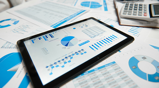 Accounting spreadsheets on paper, tablet, and computer screen.