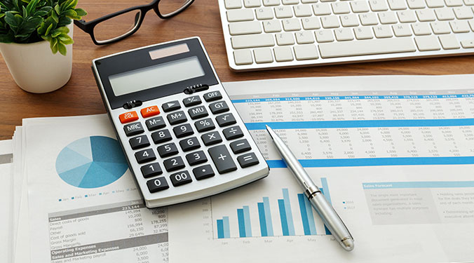 Accounting paperwork and calculator on desk. 