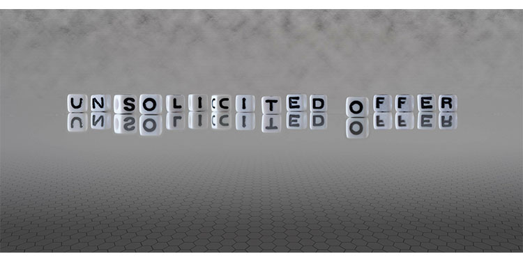 The words "unsolicited offer' spelled out on desk with white cube beads with black lettering.