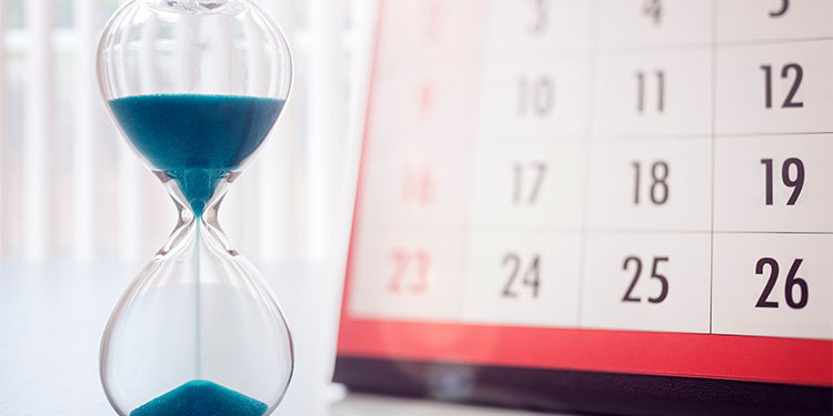 Hour glass measuring time next to a calendar. 