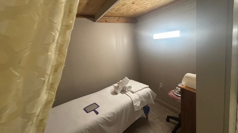 Private facial room with bed, linens, and curtain divider.