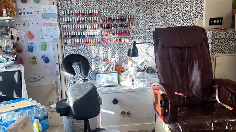 Pedicure chair with nearby portable massage chair and workstation containing tools, polish, and equipment.