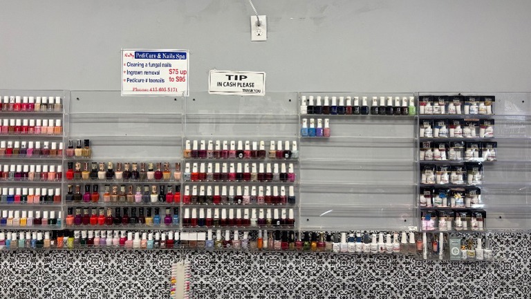 Extensive polish collection displayed on clear racks; includes hundreds of colors.
