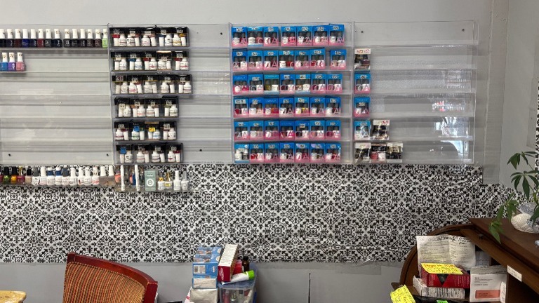 Wall-mounted shelves with organized dip powders and nail polish color samples.