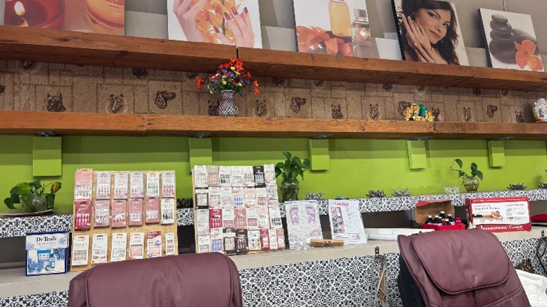 Shelving with nail kits, skincare products, small plants, and decorative prints.