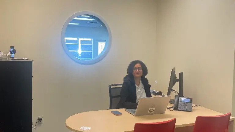 Executive Desk with Monitor and Business Attire Description: Professional workspace featuring curved executive desk, dual screens, and red guest chairs. Suited
